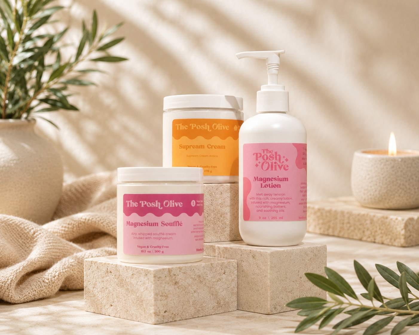 Three skincare products from The Posh, Olive Shop are arranged on beige stone blocks with a soft neutral background and decorative olive branches and a candle. The products include Magnesium Sculffle in a white jar, Magnesium Lotion in a white pump bottle, and Sunbeam Cream in a white jar with an orange label.